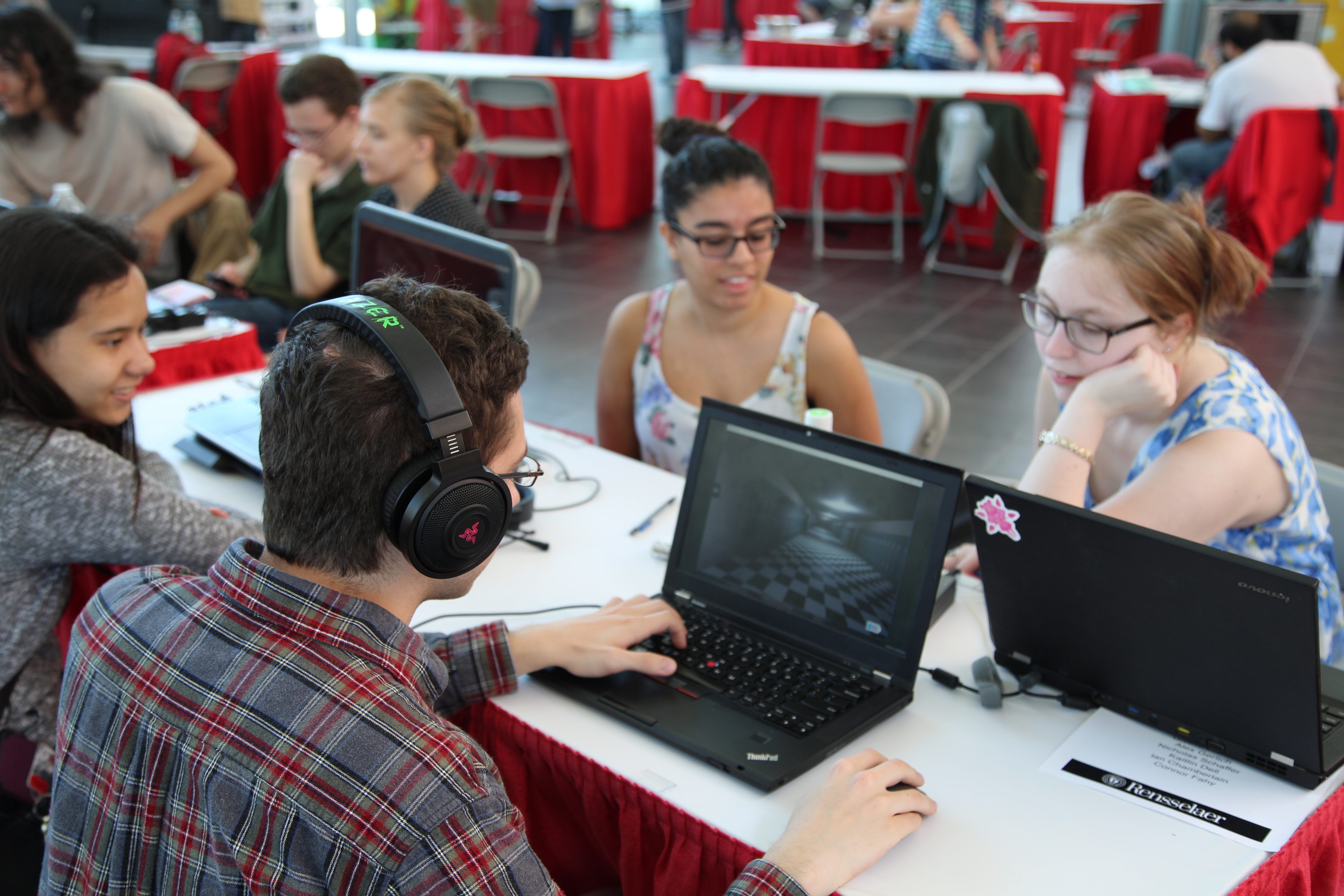 Three students watch a fourth playing a laptop game at GameFest 2016.