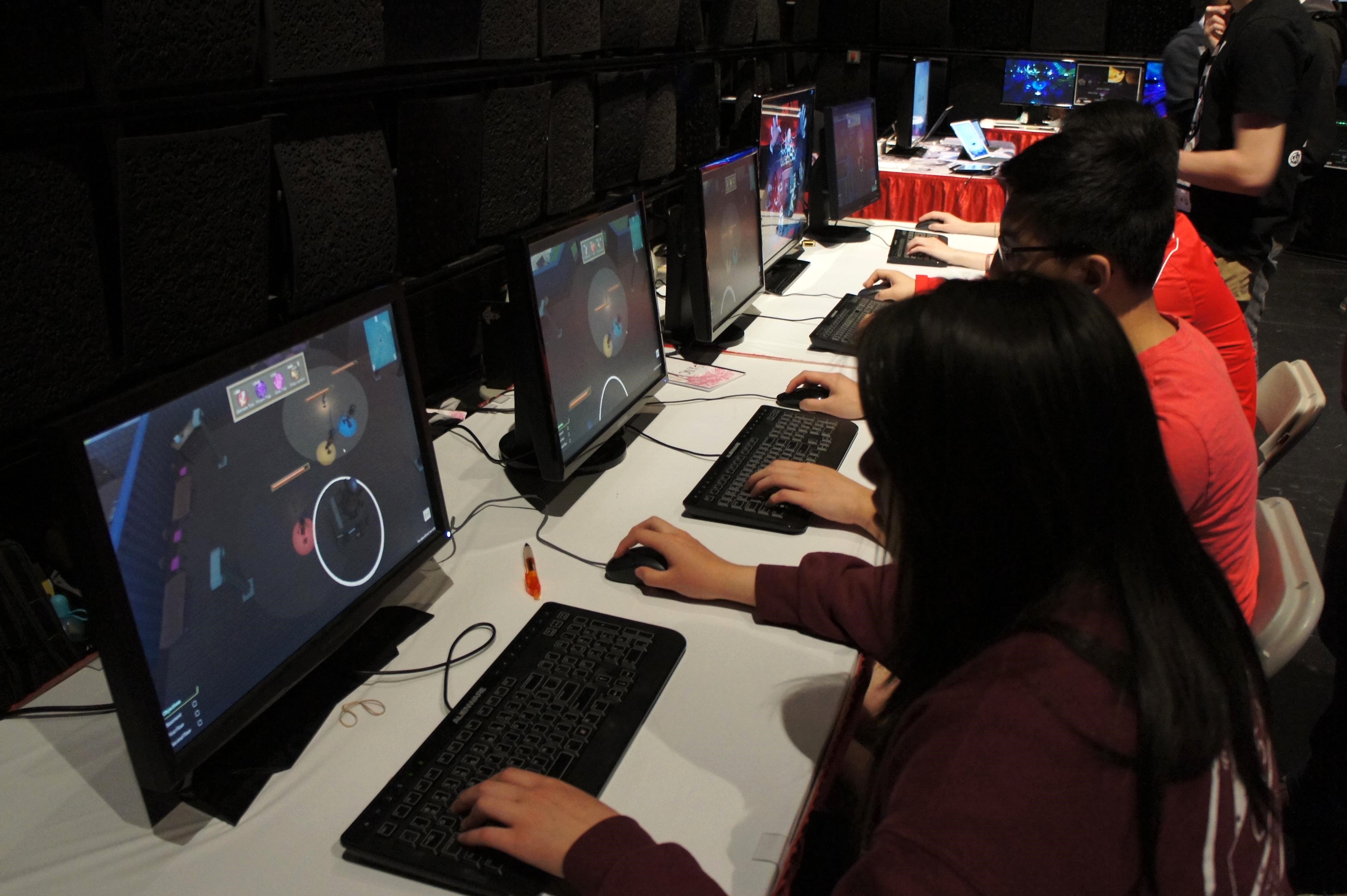 Students playing games at four booths during GameFest 2016.